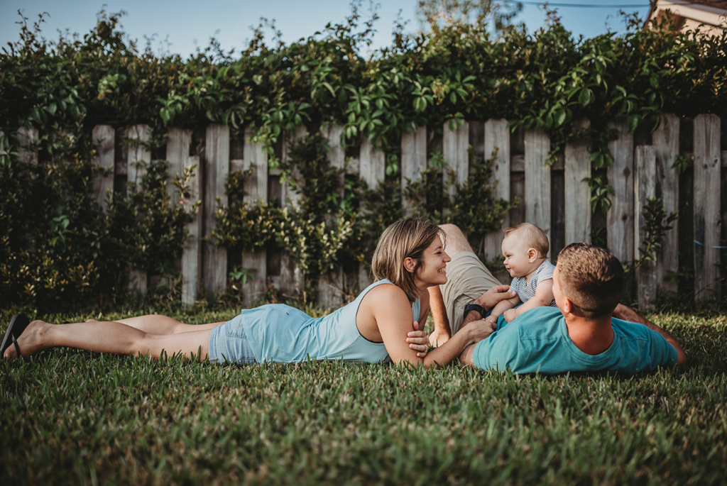 Image of a young family laying together on the grass.